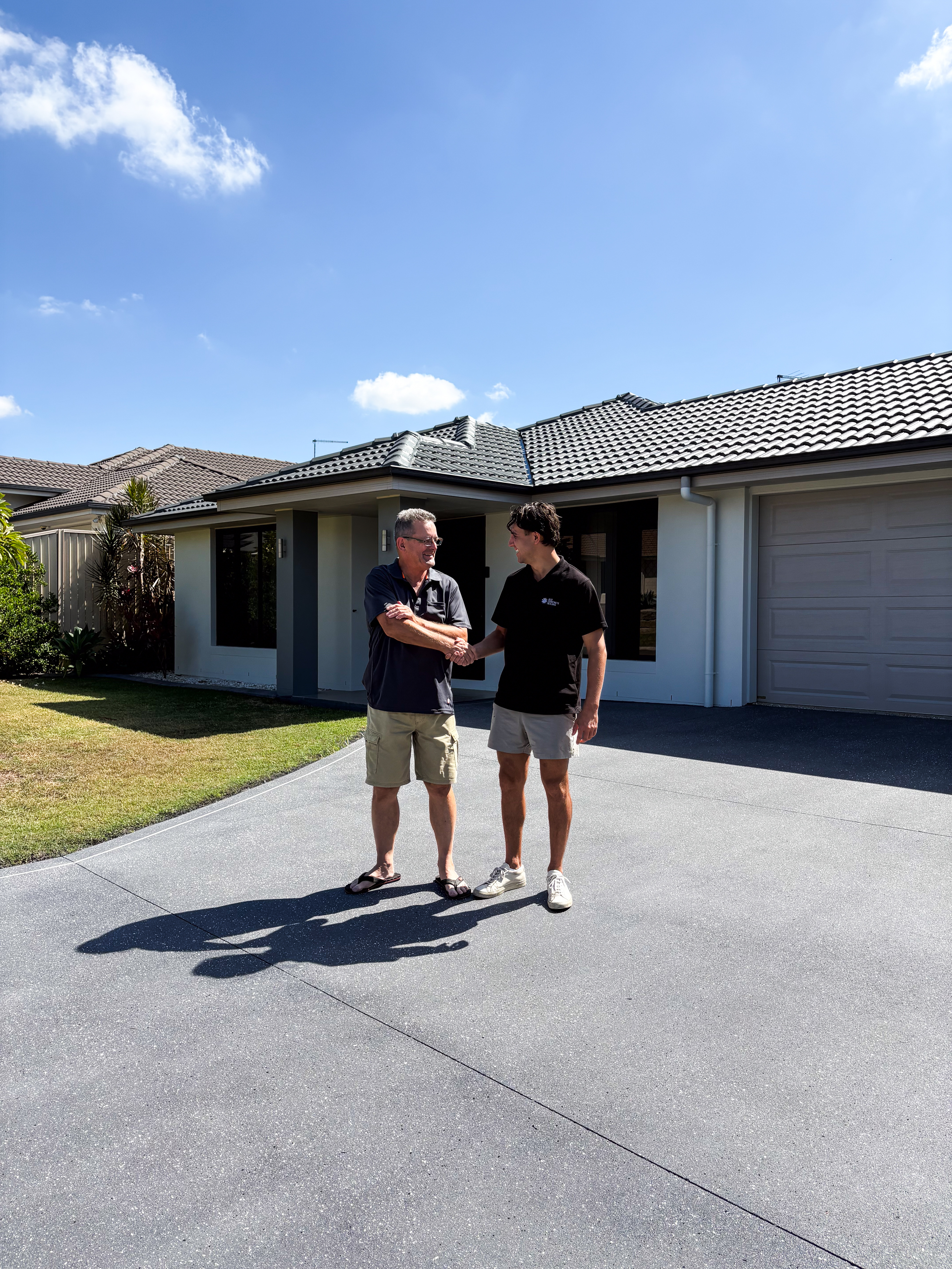 Lachlan from QLD Concrete Sealing shaking hands with a happy customer on their freshly sealed driveway